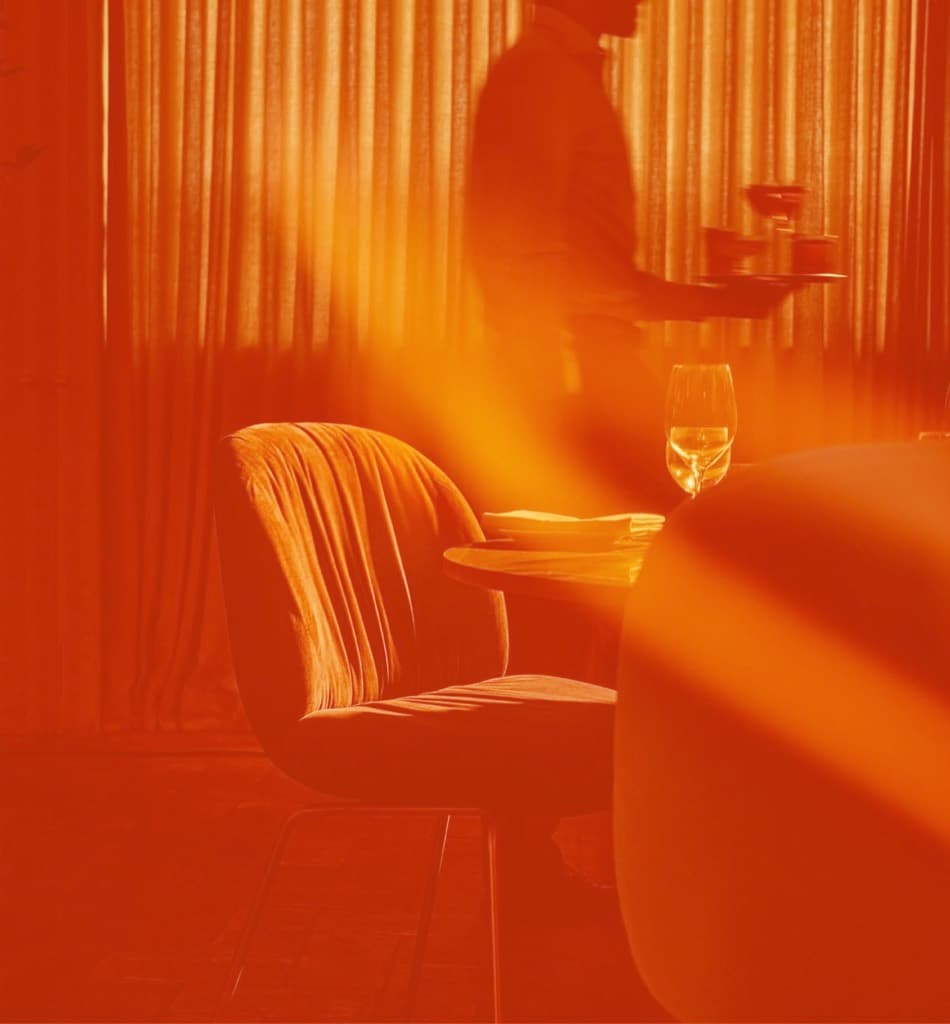 A velvet chair and champagne in the orange-lit Vaults